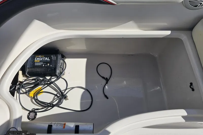 Slide: The Image of Storage compartment of a 2015 Tahoe 215 Xi boat with digital charger and cables. - 57