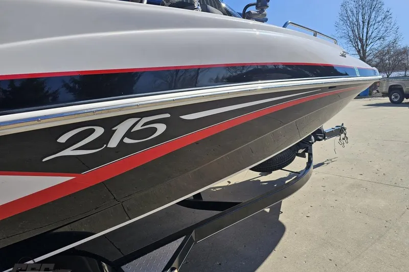 Slide: The Image of 2015 Tahoe 215 Xi boat on trailer, showcasing sleek design and bold graphics. - 8