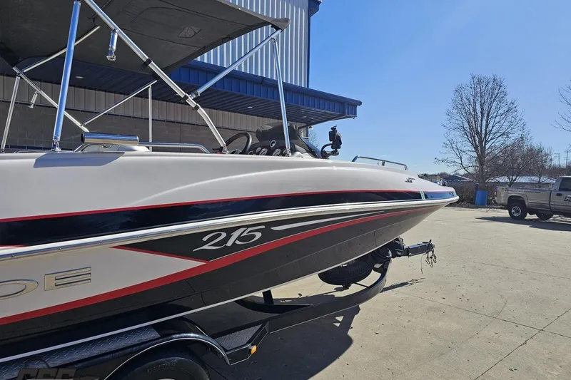 Slide: The Image of 2015 Tahoe 215 Xi boat on trailer, parked outdoors under clear blue sky. - 9