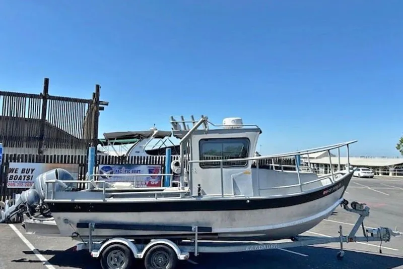 The Image of 1998 Fishing 22 boat on trailer in parking lot under clear blue sky. - 0