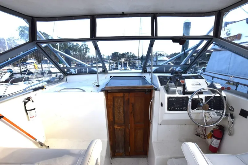 Slide: The Image of 1987 Luhrs Alura 35 boat cockpit with steering wheel, navigation equipment, and wooden cabinet. - 7