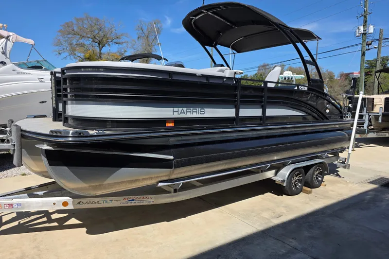 The Image of 2021 Harris Solstice 230 SL pontoon boat on trailer, parked outdoors under clear blue sky. - 0