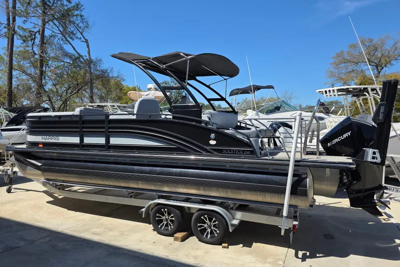 Slide: The Image of 2021 Harris Solstice 230 SL pontoon boat on trailer, featuring sleek design and Mercury engine. - 2