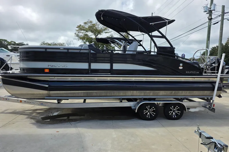 Slide: The Image of 2021 Harris Solstice 230 SL pontoon boat on trailer, featuring sleek black design. - 5