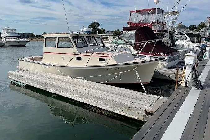 Slide: The Image of 1998 General Marine Custom Downeast boat docked at a marina under a clear sky. - 2