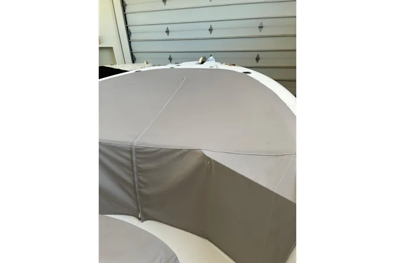 Slide: The Image of 2020 Edgewater 262CC boat with protective cover in a garage setting. - 5