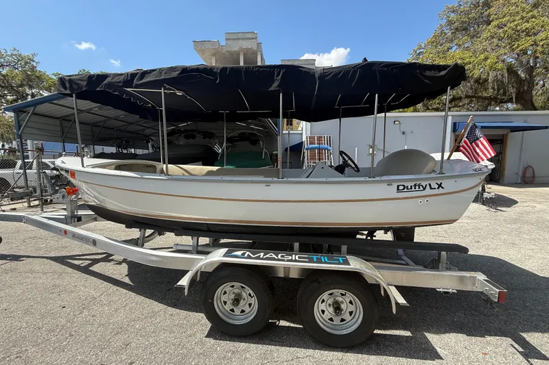 Slide: The Image of 2004 Duffy 18 electric boat on trailer with canopy, parked outdoors. - 3