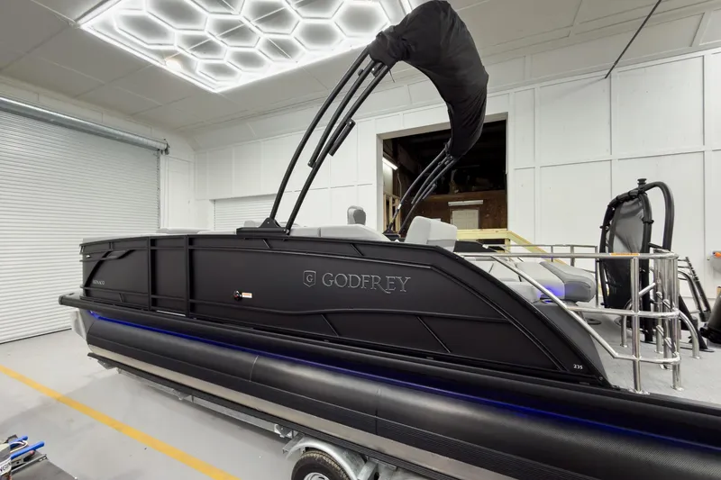 Slide: The Image of 2026 Godfrey Monaco 23' Tritoon boat in a modern indoor setting. - 11