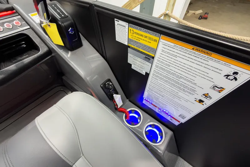 Slide: The Image of 2026 Godfrey Monaco 23' Tritoon console with warning labels and illuminated cup holders. - 26