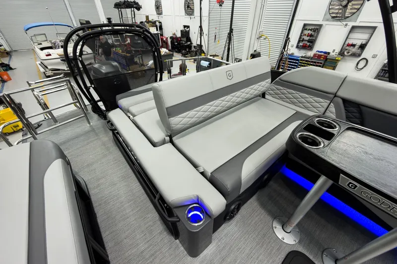 Slide: The Image of 2026 Godfrey Monaco 23' Tritoon interior with flip lounge seating and cup holders in a workshop. - 35