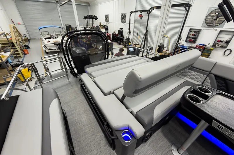 Slide: The Image of 2026 Godfrey Monaco 23' Tritoon with flip lounge, showcased in a workshop setting. - 36