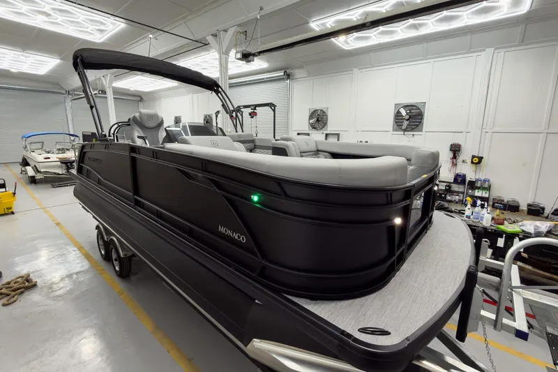 Slide: The Image of 2026 Godfrey Monaco 23' Tritoon in showroom, featuring sleek design and luxurious seating. - 4