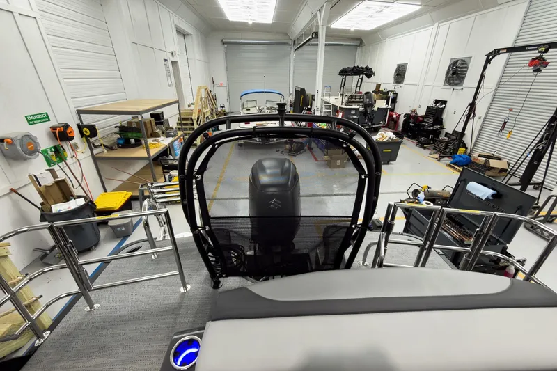 Slide: The Image of 2026 Godfrey Monaco 23' Tritoon in a workshop, showcasing its engine and interior. - 44