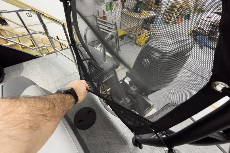 Slide: The Image of Man adjusting netting on 2026 Godfrey Monaco 23' Tritoon boat in a workshop. - 47