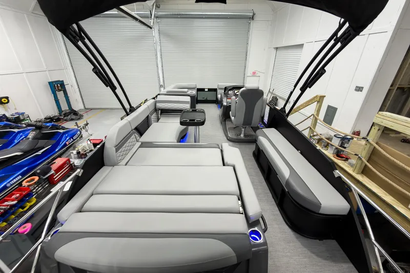 Slide: The Image of 2026 Godfrey Monaco 23' Tritoon with luxurious seating and modern design in a showroom. - 48