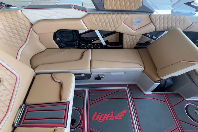 Slide: The Image of Luxurious interior of 2026 Tigé 24RZX boat with tan seating and red accents. - 31