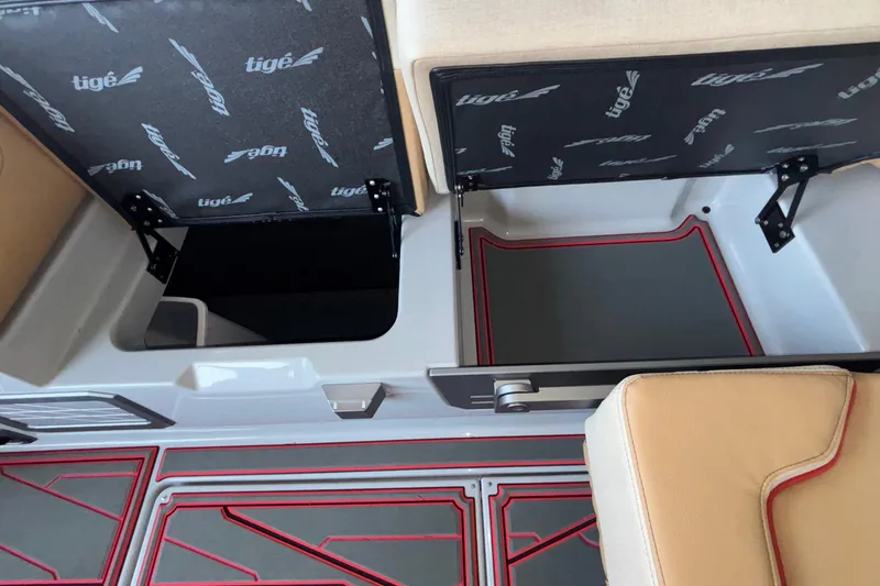Slide: The Image of 2026 Tigé 24RZX boat interior storage compartments with open lids and red-accented flooring. - 34
