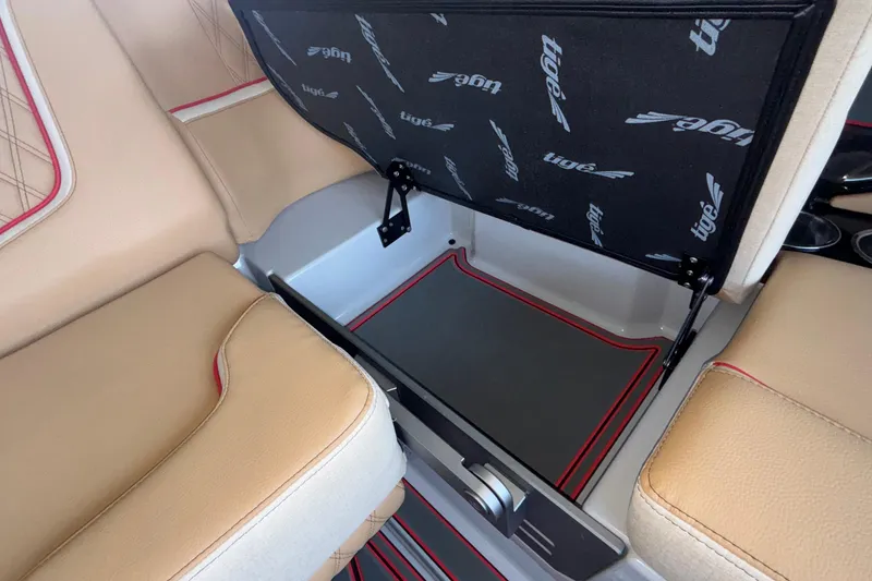 Slide: The Image of 2026 Tigé 24RZX boat interior storage compartment with beige seating and red accents. - 35