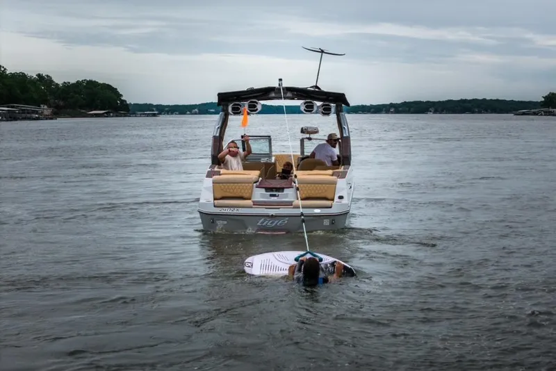 Slide: The Image of 2026 Tigé 24RZX boat towing a wakeboarder on a lake. - 2