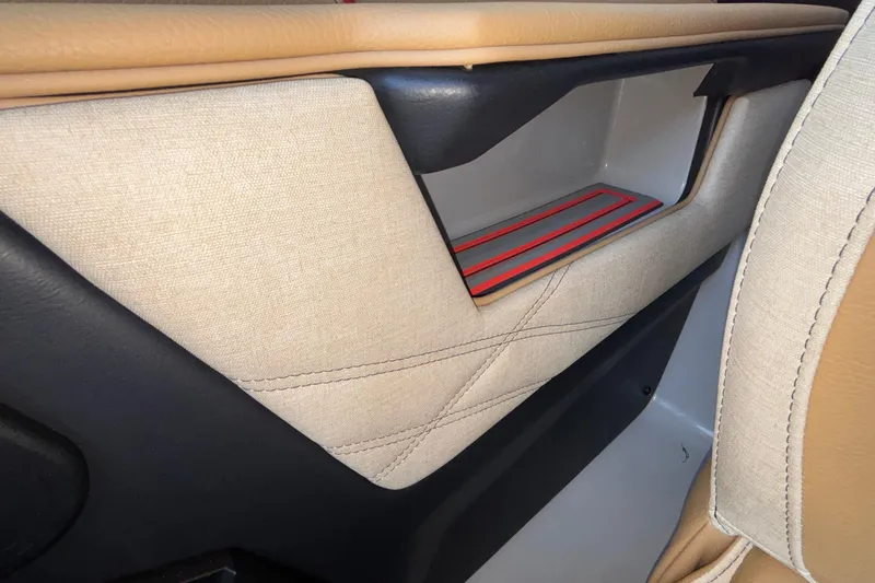 Slide: The Image of Interior detail of 2026 Tigé 24RZX boat, featuring beige and black upholstery with red accents. - 51