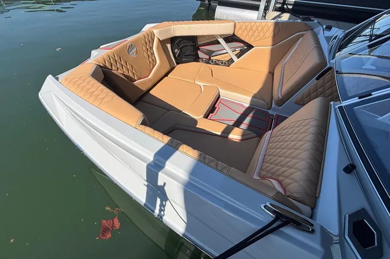 Slide: The Image of 2026 Tigé 24RZX boat interior with tan quilted seating and red accents on the water. - 62