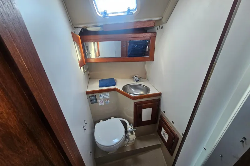 Slide: The Image of 1988 Catalina 30 MkII boat bathroom with sink, toilet, and wooden cabinetry. - 15