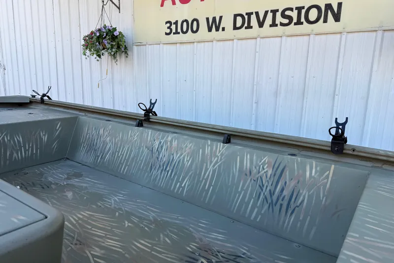 Slide: The Image of 2022 Tracker Grizzly 1648 SC boat interior with camouflage design, parked near a building. - 21