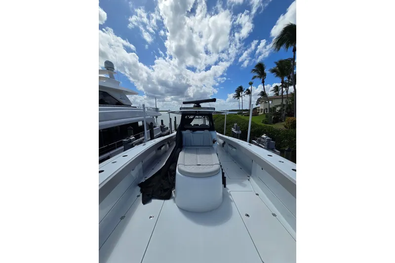 Slide: The Image of 2025 Freeman 47 boat deck under a partly cloudy sky, docked near palm trees. - 9