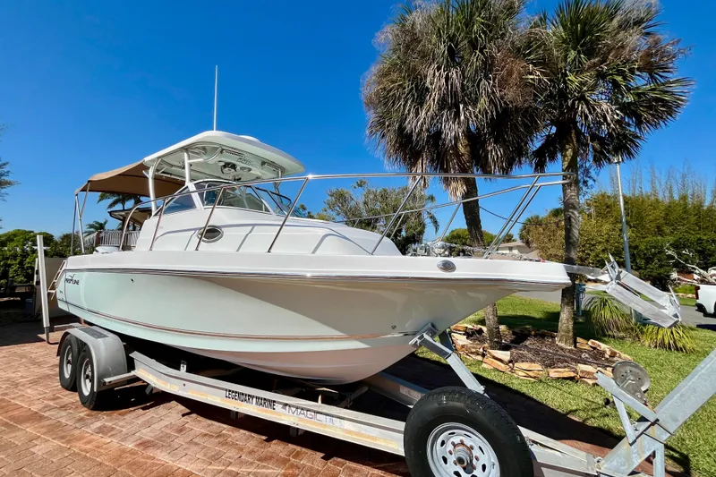 The Image of 2018 Pro-Line 26 Express boat on trailer, parked near palm trees under clear blue sky. - 1