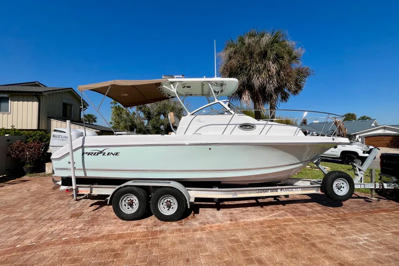 Slide: The Image of 2018 Pro-Line 26 Express boat on trailer, parked in driveway under clear blue sky. - 2
