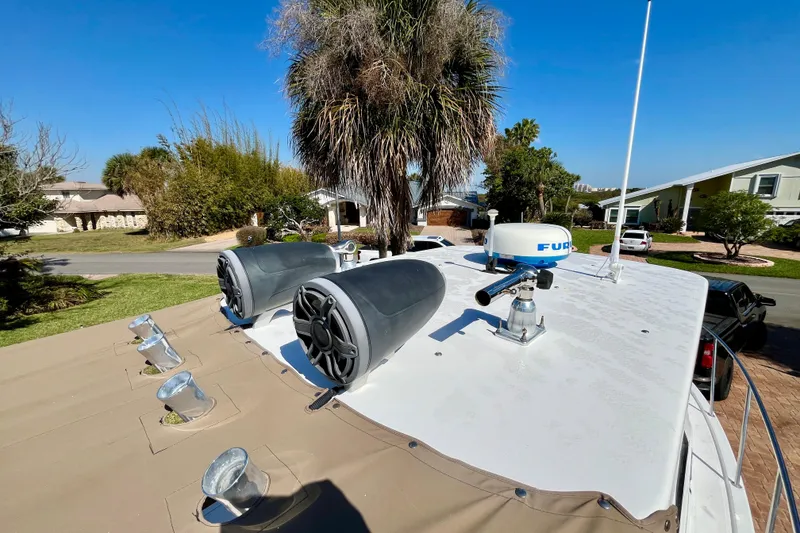 Slide: The Image of 2018 Pro-Line 26 Express boat roof with speakers and radar, surrounded by suburban greenery. - 46