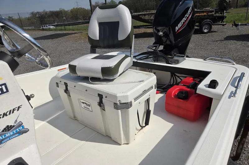 Slide: The Image of 2021 Mako Pro Skiff 15 CC boat interior with seat, cooler, and Mercury engine. - 16