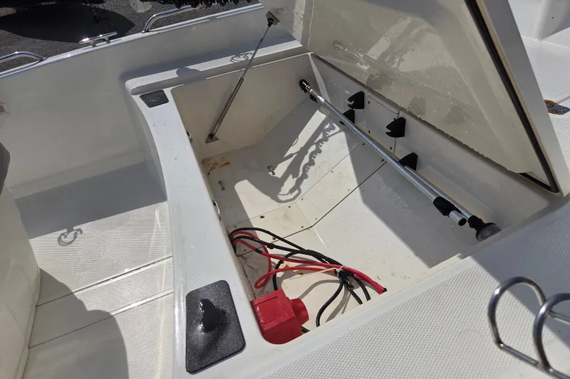 Slide: The Image of Open storage compartment in 2021 Mako Pro Skiff 15 CC boat, showing wiring and rod holders. - 9