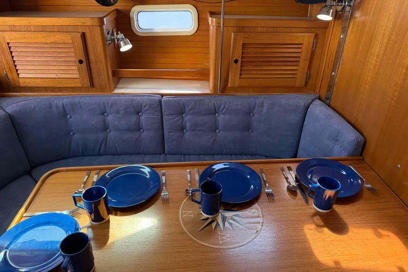 Slide: The Image of Dining area in 1995 Catalina 36 MkII sailboat with blue tableware and wooden cabinetry. - 12