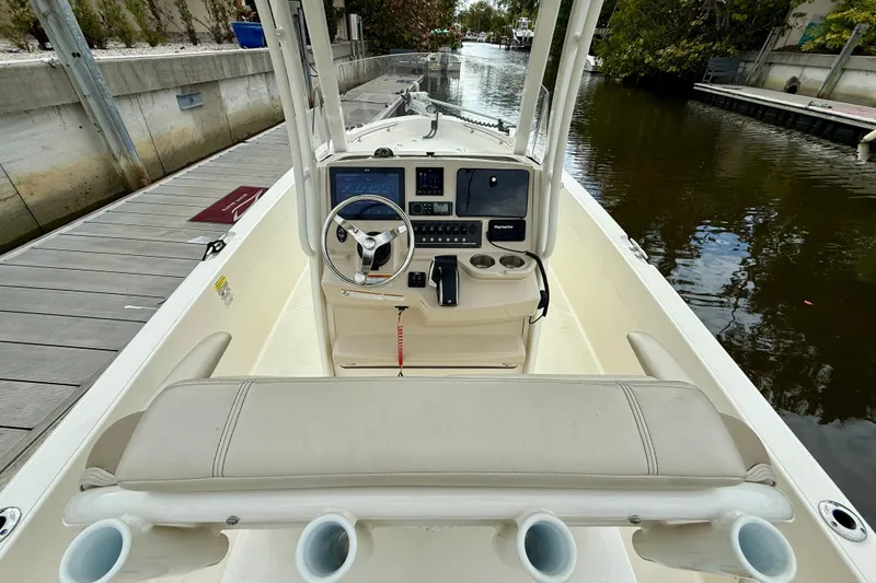 Slide: The Image of 2022 Boston Whaler 220 Dauntless boat interior with steering console and seating, docked by a canal. - 22
