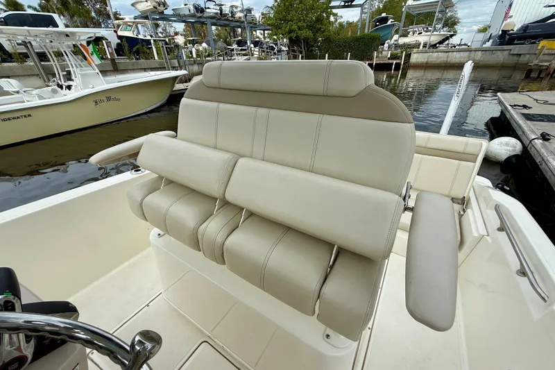 Slide: The Image of 2022 Boston Whaler 220 Dauntless boat interior with beige seating at a marina. - 25