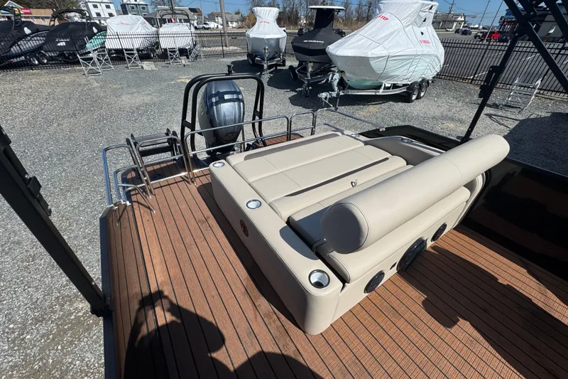 Slide: The Image of 2026 Bentley Pontoons Legacy 243 Swingback with beige seating and wood deck, parked outdoors. - 20