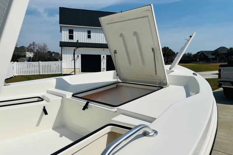 Slide: The Image of 2022 Bay Rider 239 Bay boat with open storage compartment, parked near a modern house. - 13