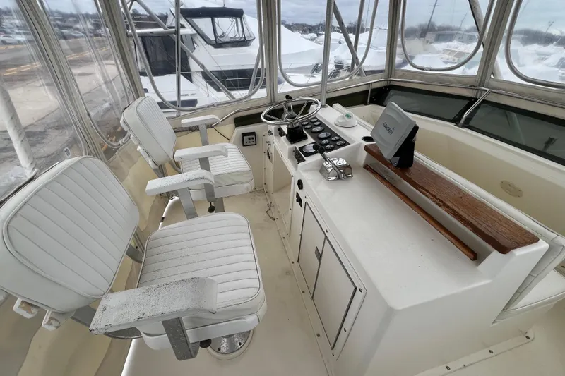 Slide: The Image of 1989 Egg Harbor 35 Sport Fisherman cockpit with steering wheel, controls, and white seating. - 3