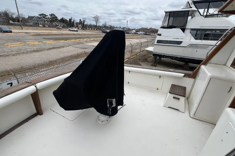 Slide: The Image of 1989 Egg Harbor 35 Sport Fisherman boat deck with covered equipment, docked near other vessels. - 8