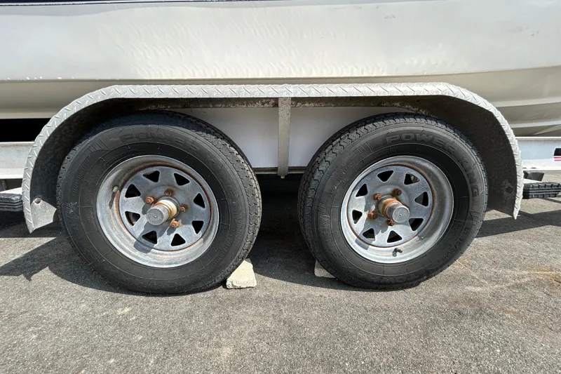 Slide: The Image of Trailer wheels of a 2006 Boston Whaler 205 Conquest boat on pavement. - 74
