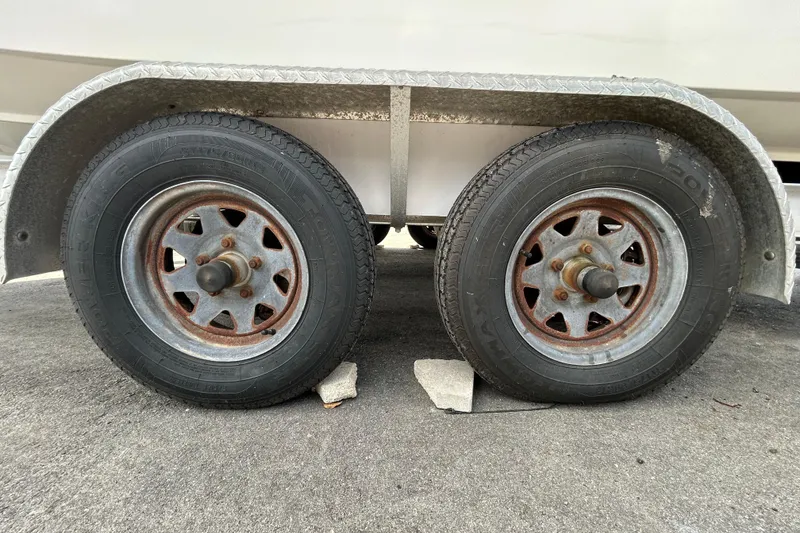 Slide: The Image of Trailer wheels of a 2006 Boston Whaler 205 Conquest boat on pavement. - 75