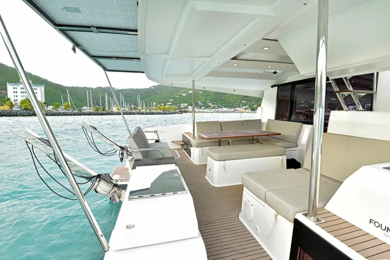 Slide: The Image of 2024 Fountaine Pajot Astrea 42 yacht with spacious deck and seating, docked by scenic marina. - 4