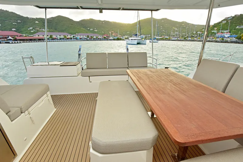 Slide: The Image of 2024 Fountaine Pajot Astrea 42 yacht deck with seating and table, overlooking marina. - 7