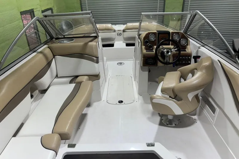 Slide: The Image of 2014 Starcraft Crossover 230 SCX IO boat interior with beige seating and modern dashboard. - 10