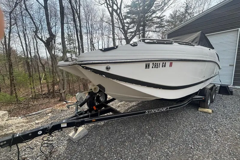 Slide: The Image of 2014 Starcraft Crossover 230 SCX IO boat on trailer, parked near trees. - 4