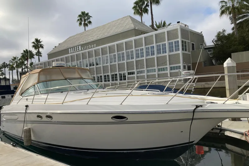 The Image of 1996 Maxum 4100 SCR yacht docked near a waterfront restaurant with palm trees. - 1