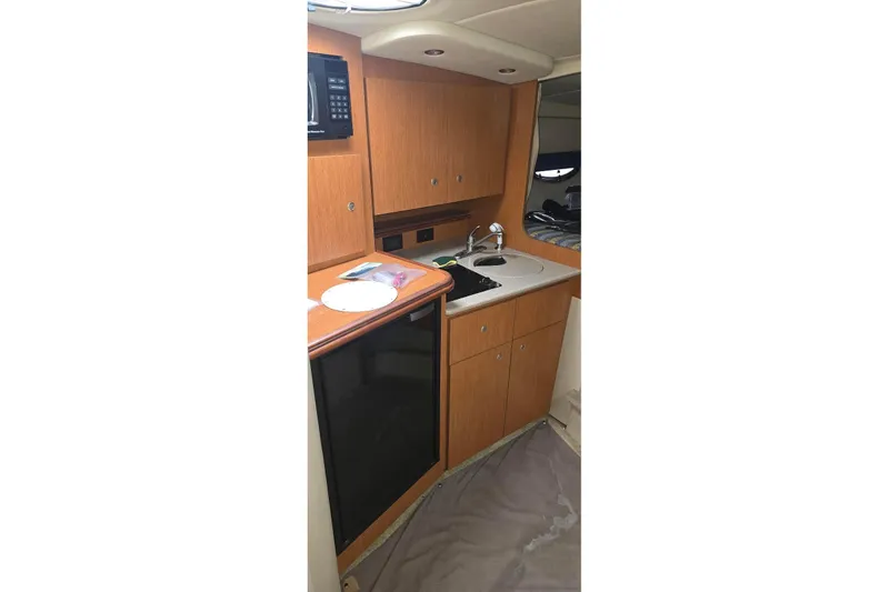 Slide: The Image of 2004 Cruisers 320 Express yacht interior kitchen with wood cabinets and compact appliances. - 12