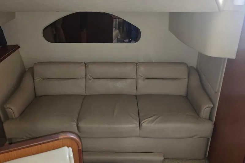 Slide: The Image of 2004 Cruisers 320 Express interior with beige leather sofa and oval window. - 13