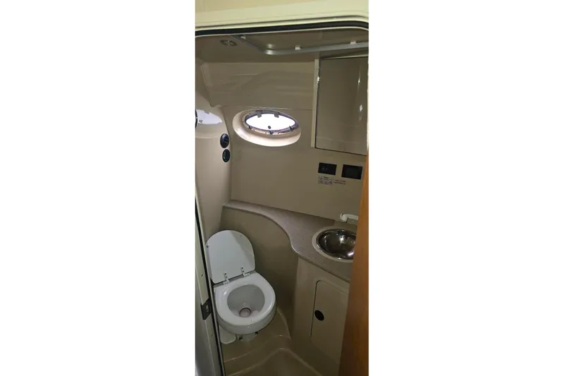 Slide: The Image of 2004 Cruisers 320 Express boat bathroom with toilet, sink, and porthole window. - 14